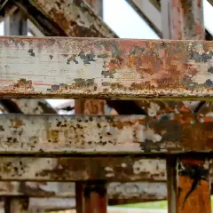 Widoczne są zardzewiałe, metalowe belki konstrukcyjne. To przykład, co to jest korozja – proces niszczenia metalu pod wpływem czynników atmosferycznych.