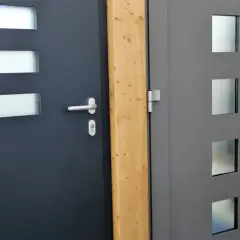 Dwie nowoczesne drzwi wejściowe, ciemnoszare i szare, z przeszkleniami. Dowiedz się, jak uszczelnić drzwi wejściowe, by zapewnić ciepło.