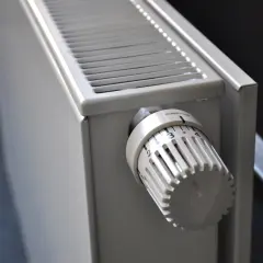 Biały termostat na grzejniku pokazuje, jak ustawić termostat na grzejniku, ustawiając pokrętło na pożądaną temperaturę.