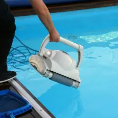 Czyszczenie basenu ogrodowego po sezonie: robot do czyszczenia zanurzany w wodzie.