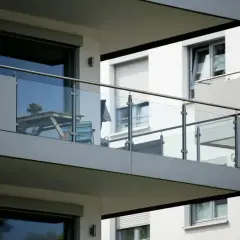Nowoczesny balkon loggia z przeszkloną balustradą, stolikiem i krzesłem.