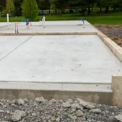 Nowa płyta fundamentowa warstwy betonu z wystającymi rurkami hydraulicznymi, gotowa na budowę domu.