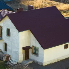 Nowy dom w zabudowie siedliskowej, z ciemnobrązowym dachem i jasnymi ścianami, czeka na wykończenie.