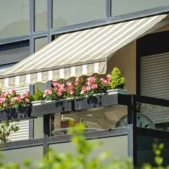 Zadaszenia balkonowe w paski chronią kwitnące pelargonie. Balkon z roślinnością i meblami.