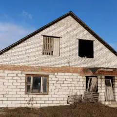 Dom w budowie, z pustymi oknami i drzwiami, czeka na rozbiórkę budynku grożącego zawaleniem.