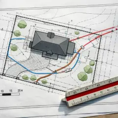 Projekt zagospodarowania terenu z domem, drzewami i zaznaczonymi instalacjami. Widoczna linijka geodezyjna.