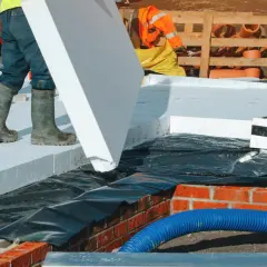 Budowlańcy układają płyty styropianu na stropie betonowym. Dużo styropianu na stropie betonowym to dobra izolacja.