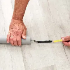 Ręce przygotowują kabel do przeciągnięcia przez peszel. Końcówka kabla owinięta taśmą jest wkładana do szarej rury.