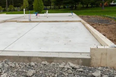 Nowa płyta fundamentowa warstwy betonu z wystającymi rurkami hydraulicznymi, gotowa na budowę domu.