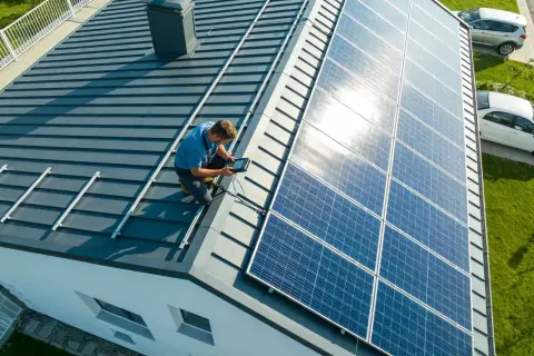 Instalator sprawdza montaż paneli słonecznych na dachu, pokazując, jak zrobić panel słoneczny.