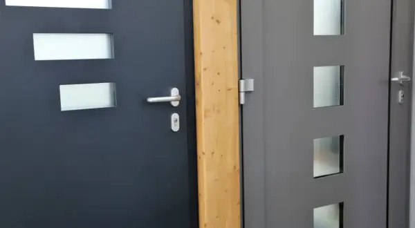 Dwie nowoczesne drzwi wejściowe, ciemnoszare i szare, z przeszkleniami. Dowiedz się, jak uszczelnić drzwi wejściowe, by zapewnić ciepło.