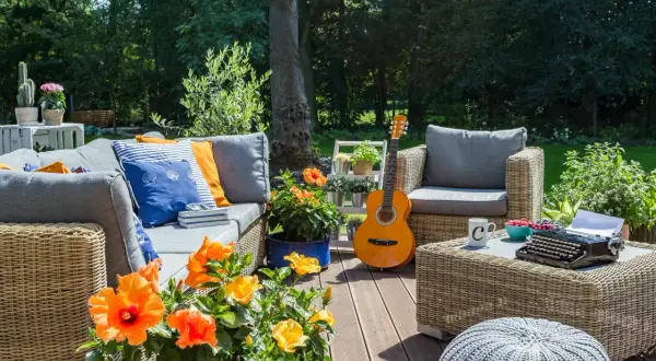 Urocza aranżacja działki rekreacyjnej: wygodna sofa, fotele, stolik z maszyną do pisania i gitara.