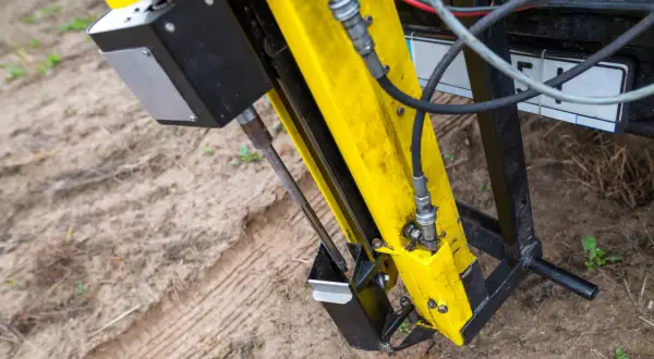 Żółta maszyna na ziemi, gotowa do pracy. Czy badania geotechniczne są obowiązkowe? Ten sprzęt pomoże to ustalić.