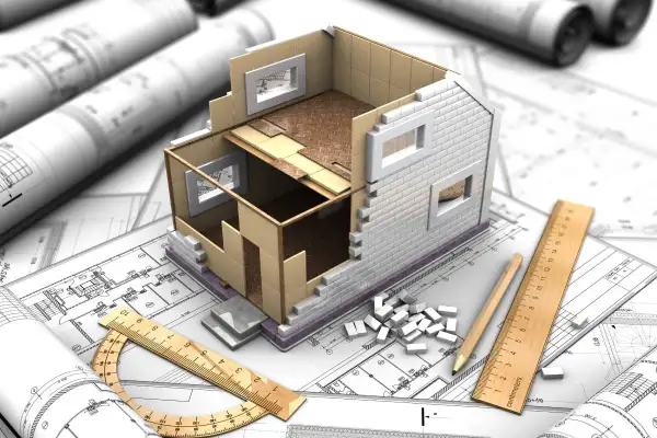 Model domu w przekroju na planach architektonicznych, narzędzia budowlane i małe cegiełki. Wizualizacja projektu budowlanego, który może być początkiem samowoli budowlanej.